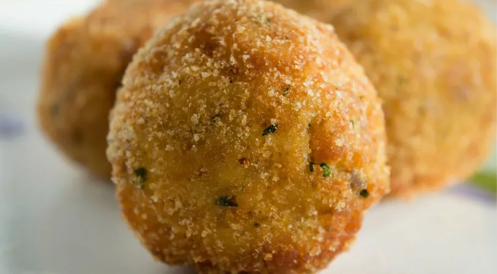 A halved Palermo arancina showing saffron rice around a ragù filling