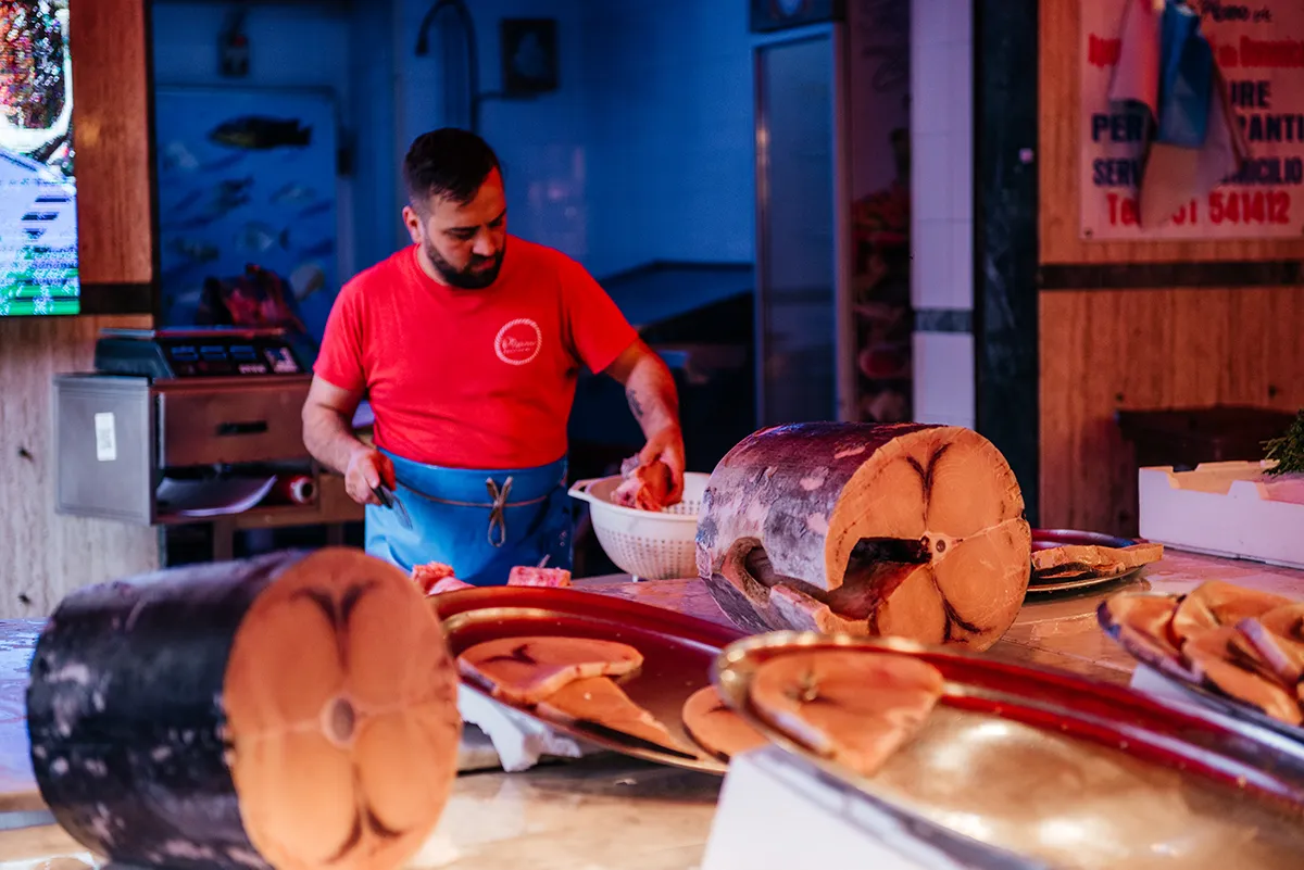 A fishmonger cutting a whole tuna at a Palermo market