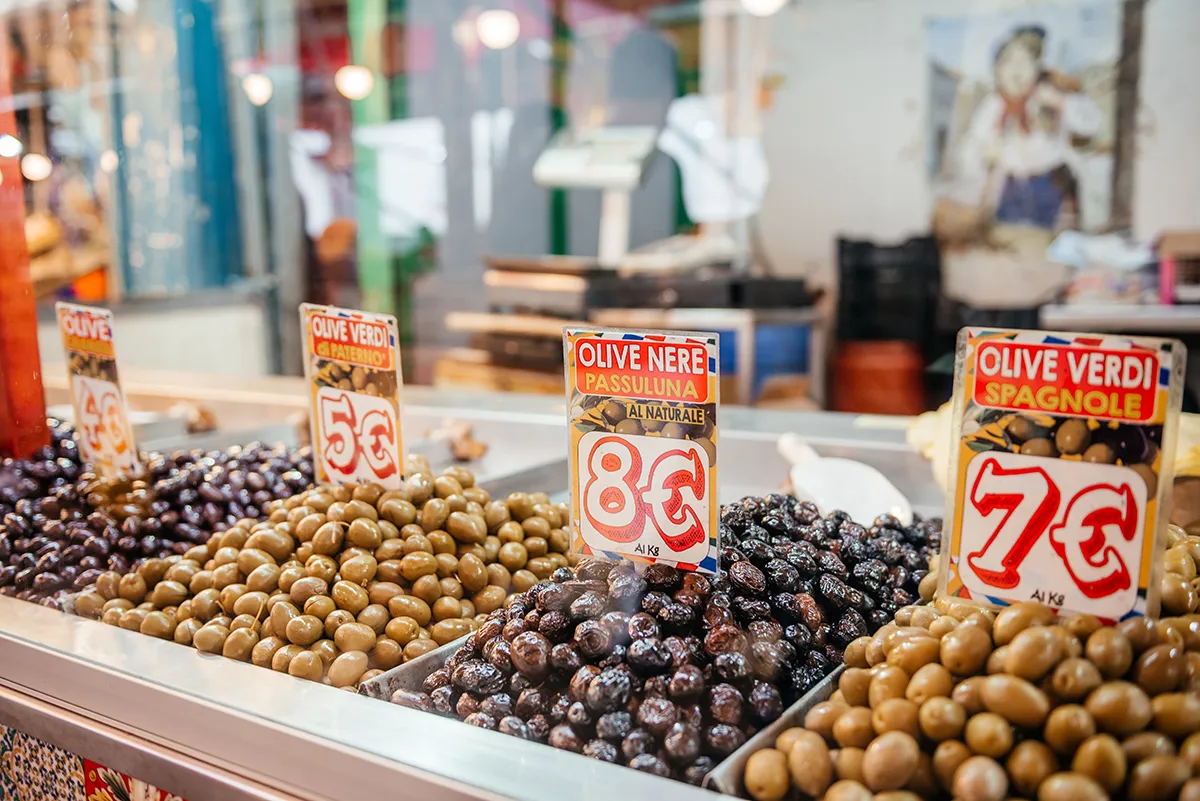 Bowls of green and black olives priced at a market stall