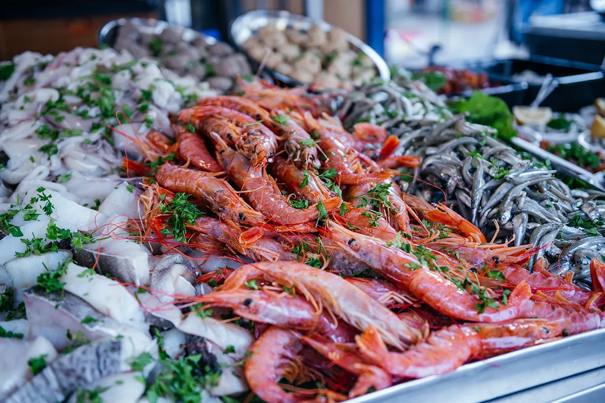 Red prawns piled on a market counter with parsley