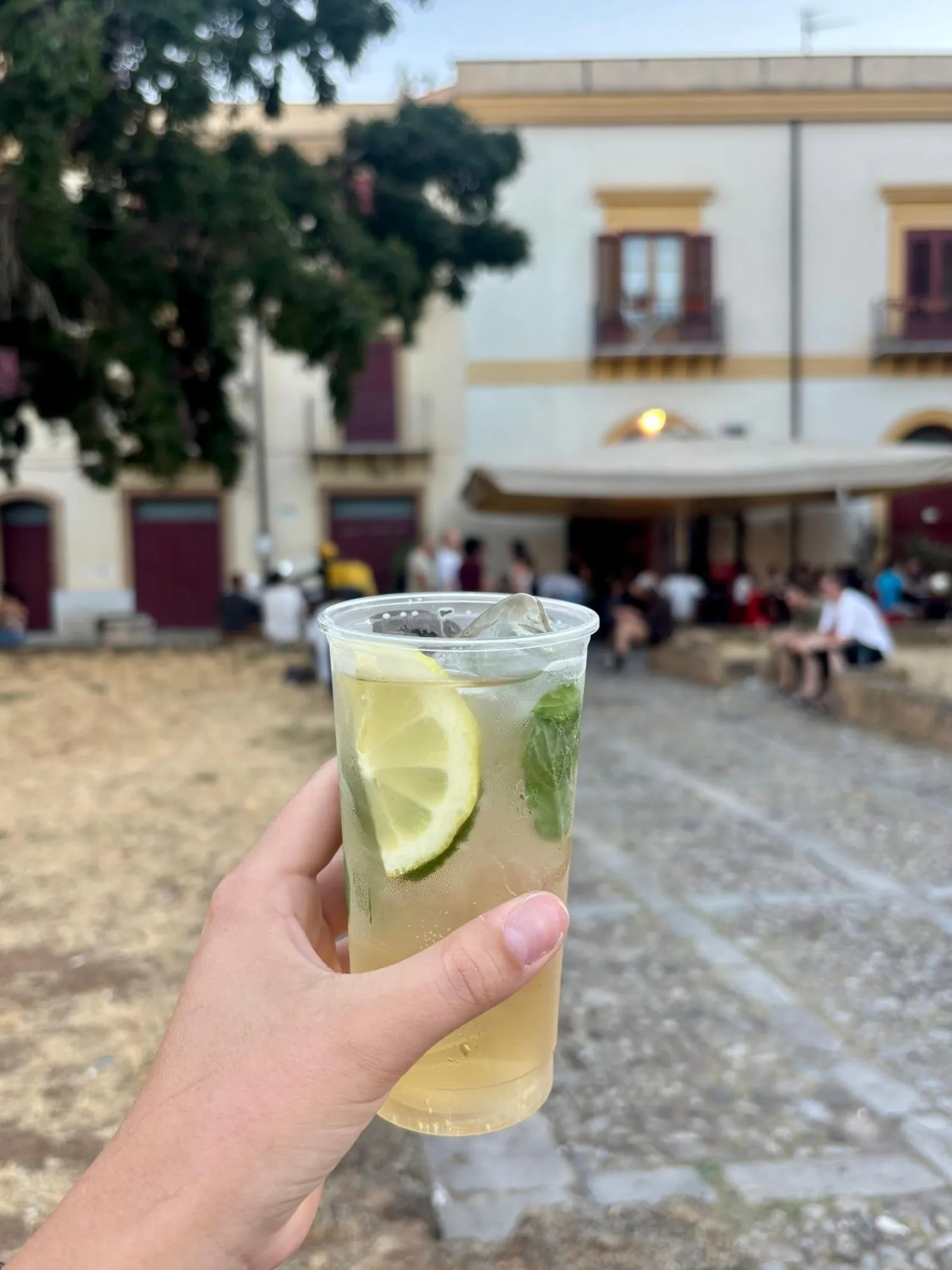 A cold drink with lime held up in a Palermo piazza