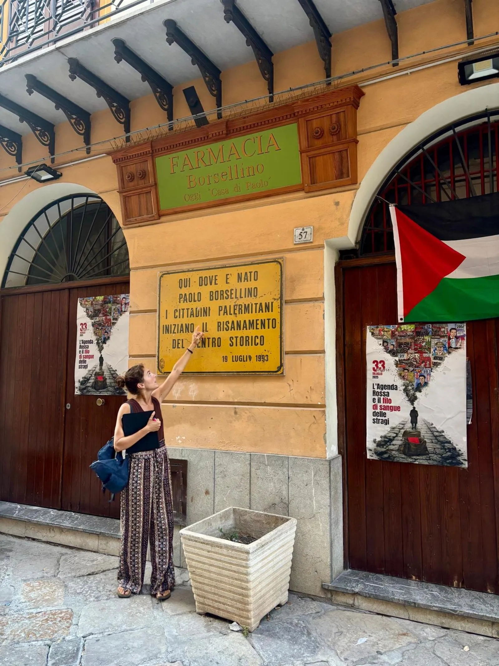 The guide beside an anti-mafia memorial plaque