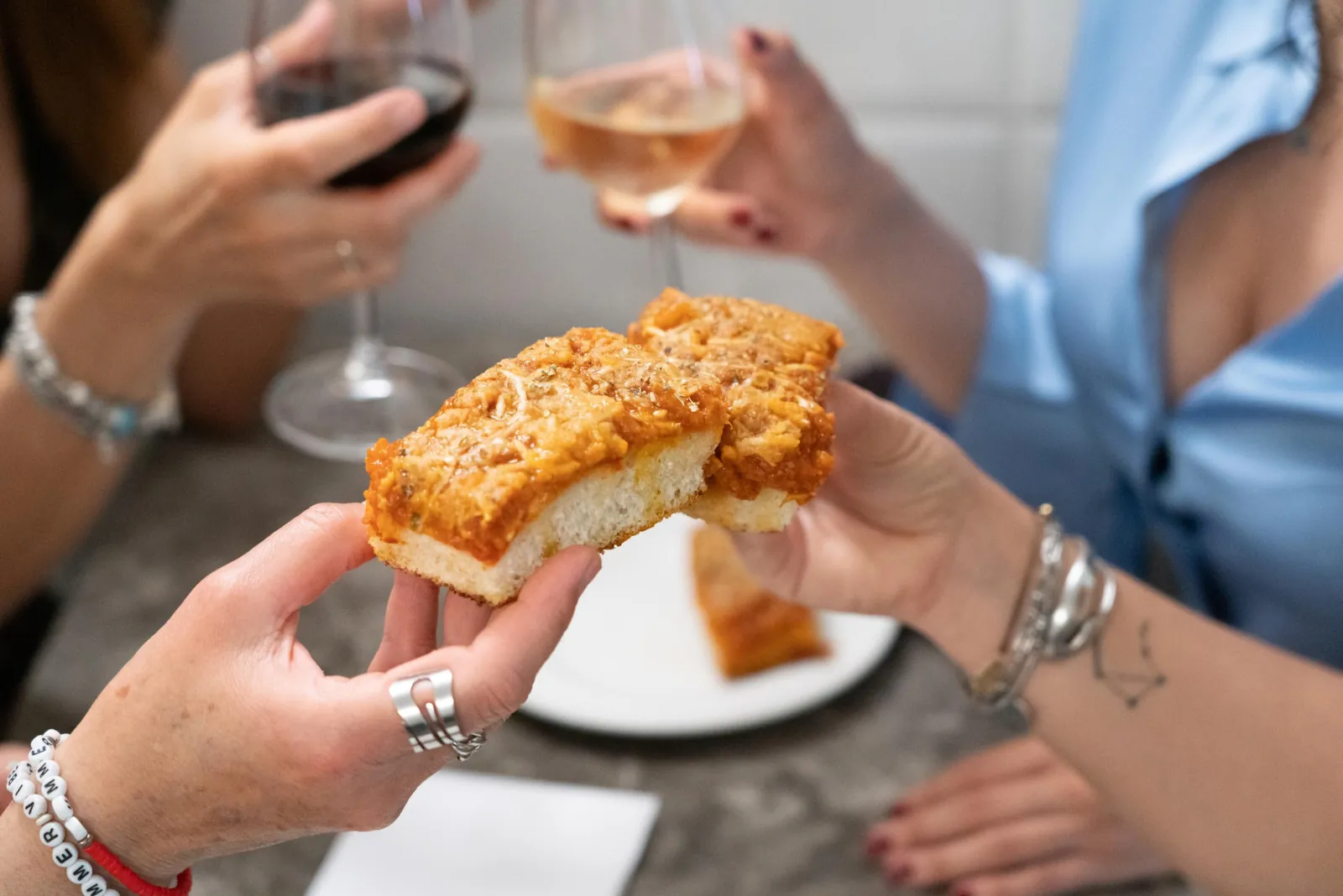 Two slices of sfincione shared over glasses of wine