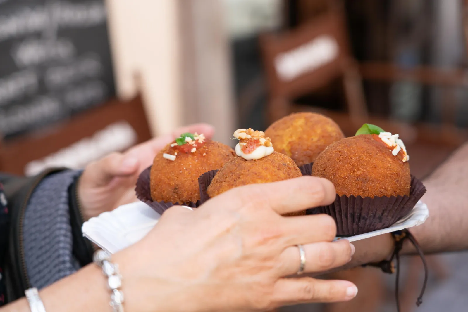 A hand holding three arancine at the tasting stop
