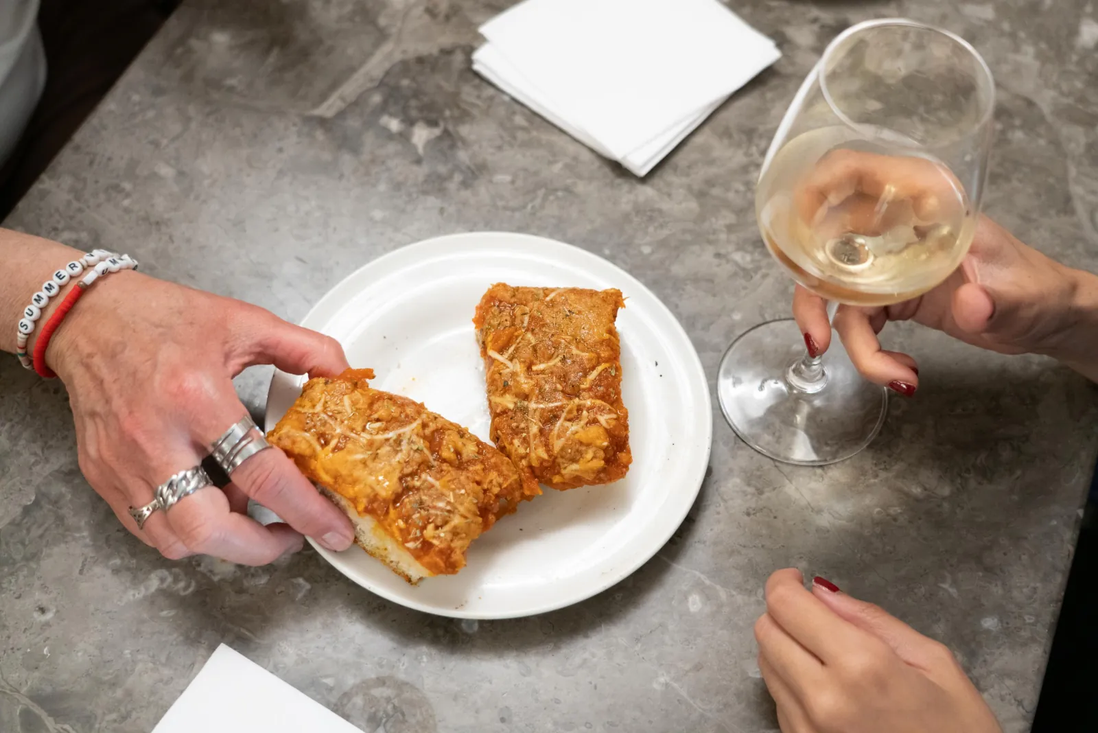 A plate of sfincione served with a glass of white wine