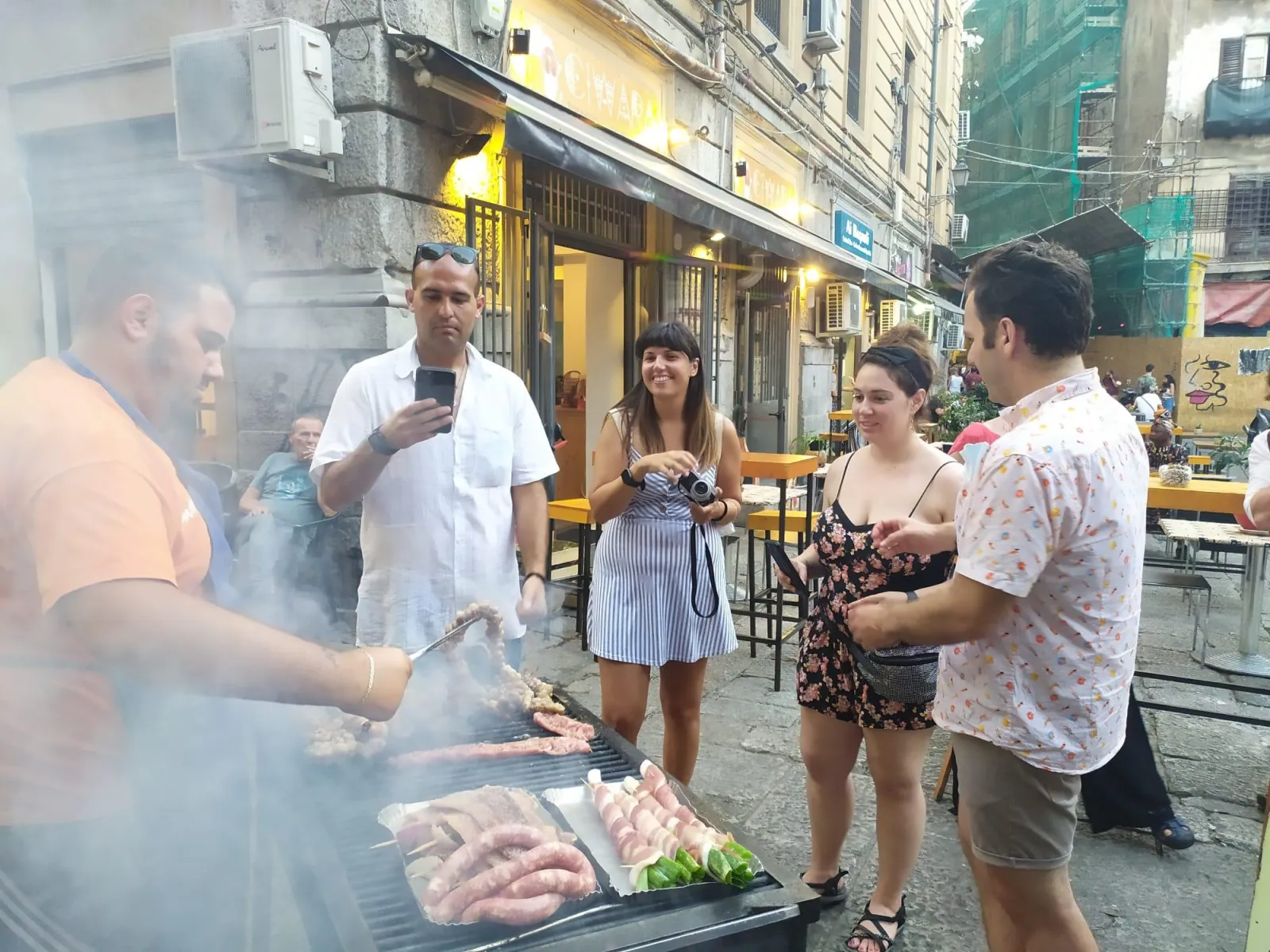 Grilled stigghiola and sausages on a smoking street barbecue at night