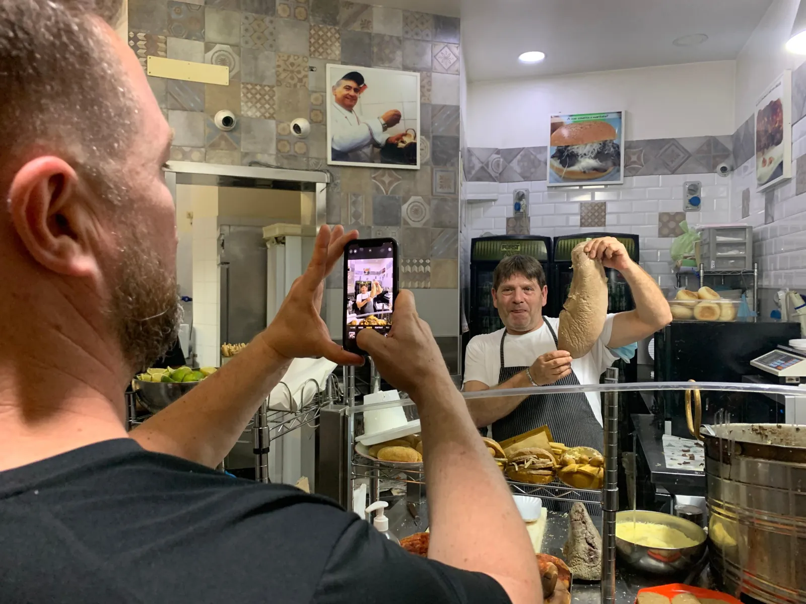 A guest photographs a counterman at a Palermo snack bar