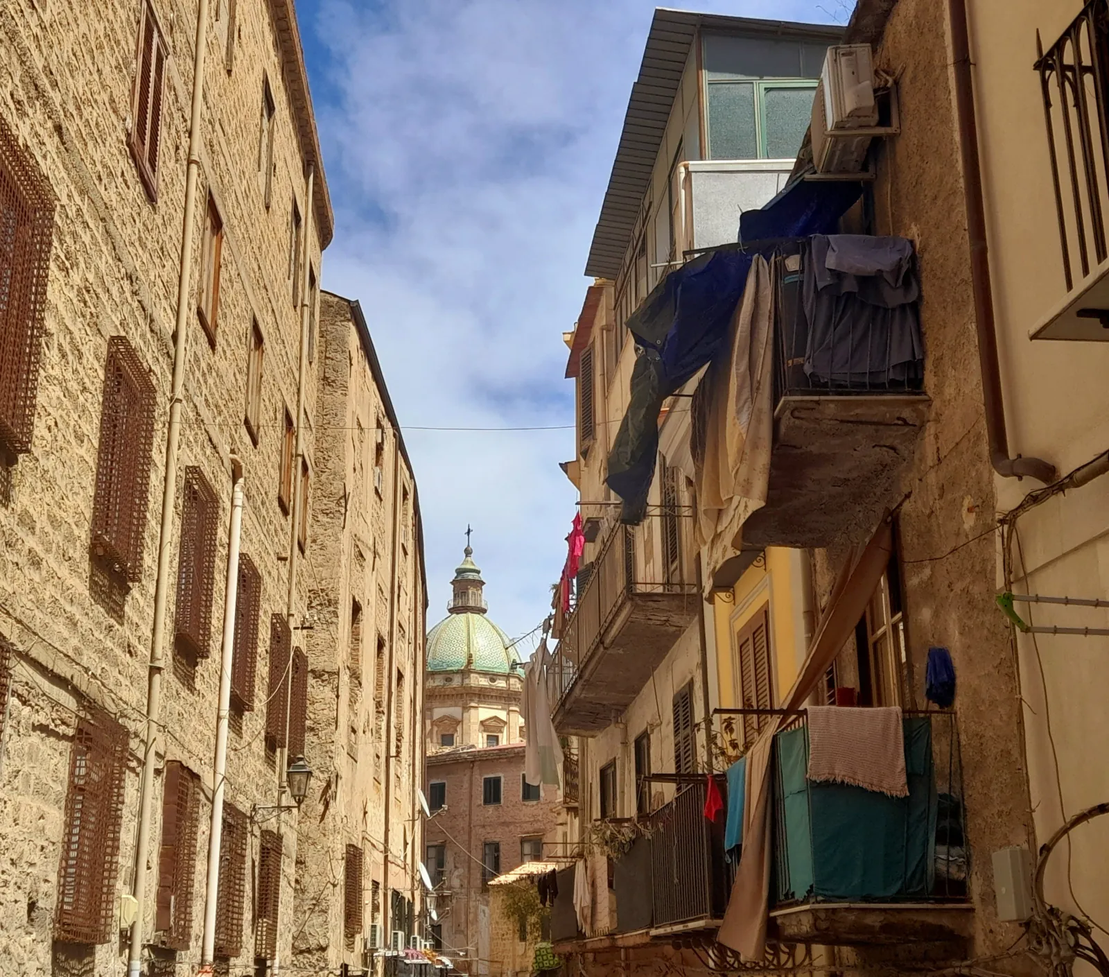 A narrow old-town street with a church dome at the end