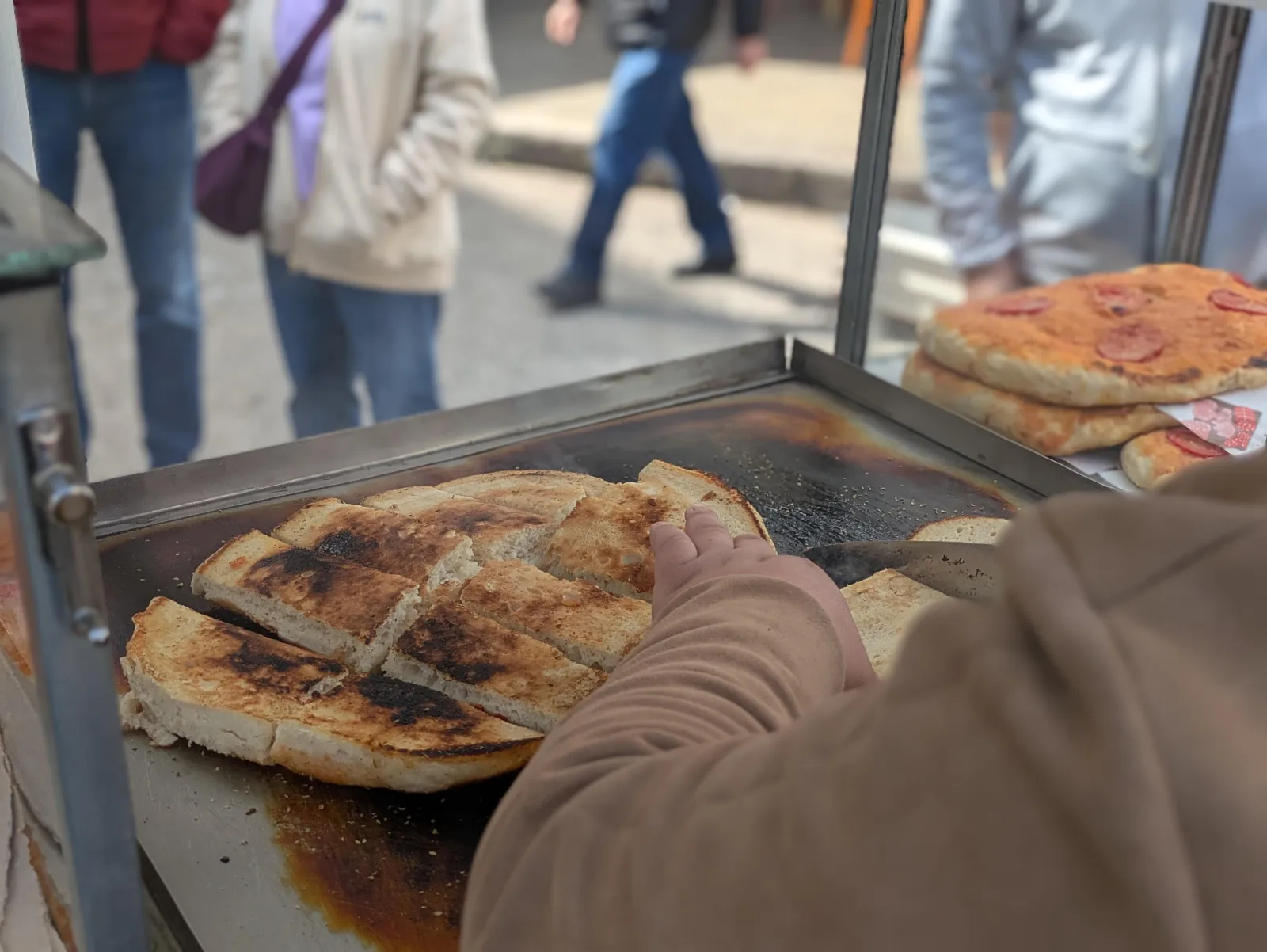 Sfincione warming on the hot plate of a street food cart