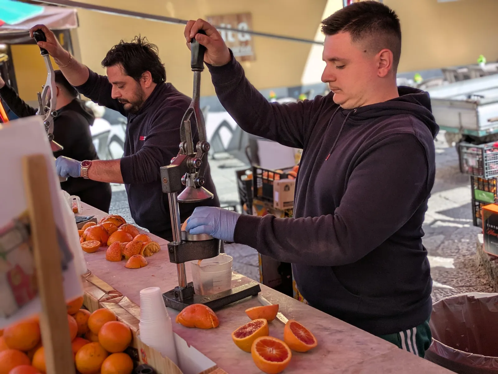 A vendor presses fresh blood orange juice at a market stall