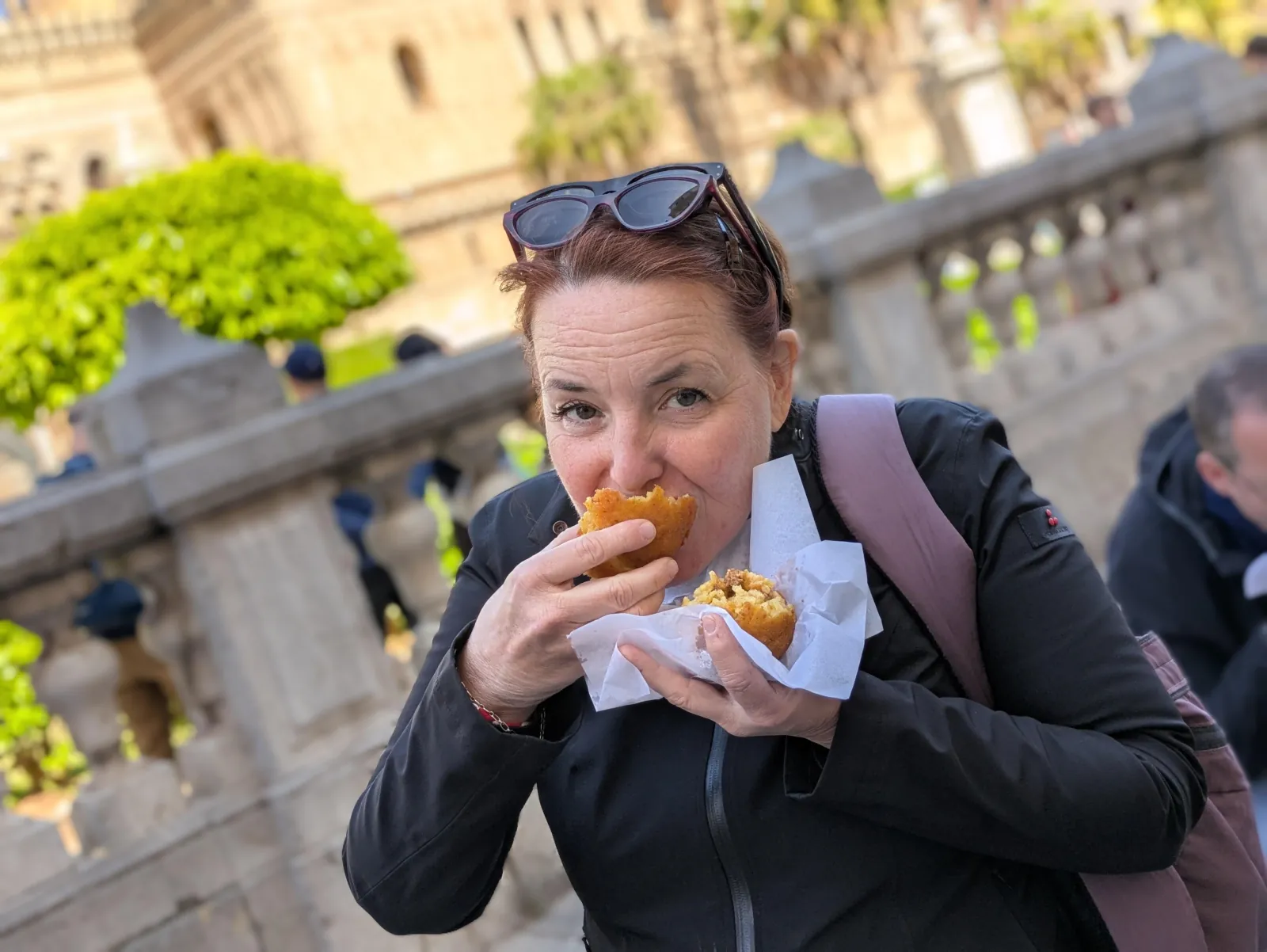A guest takes a first bite of an arancina outside the cathedral