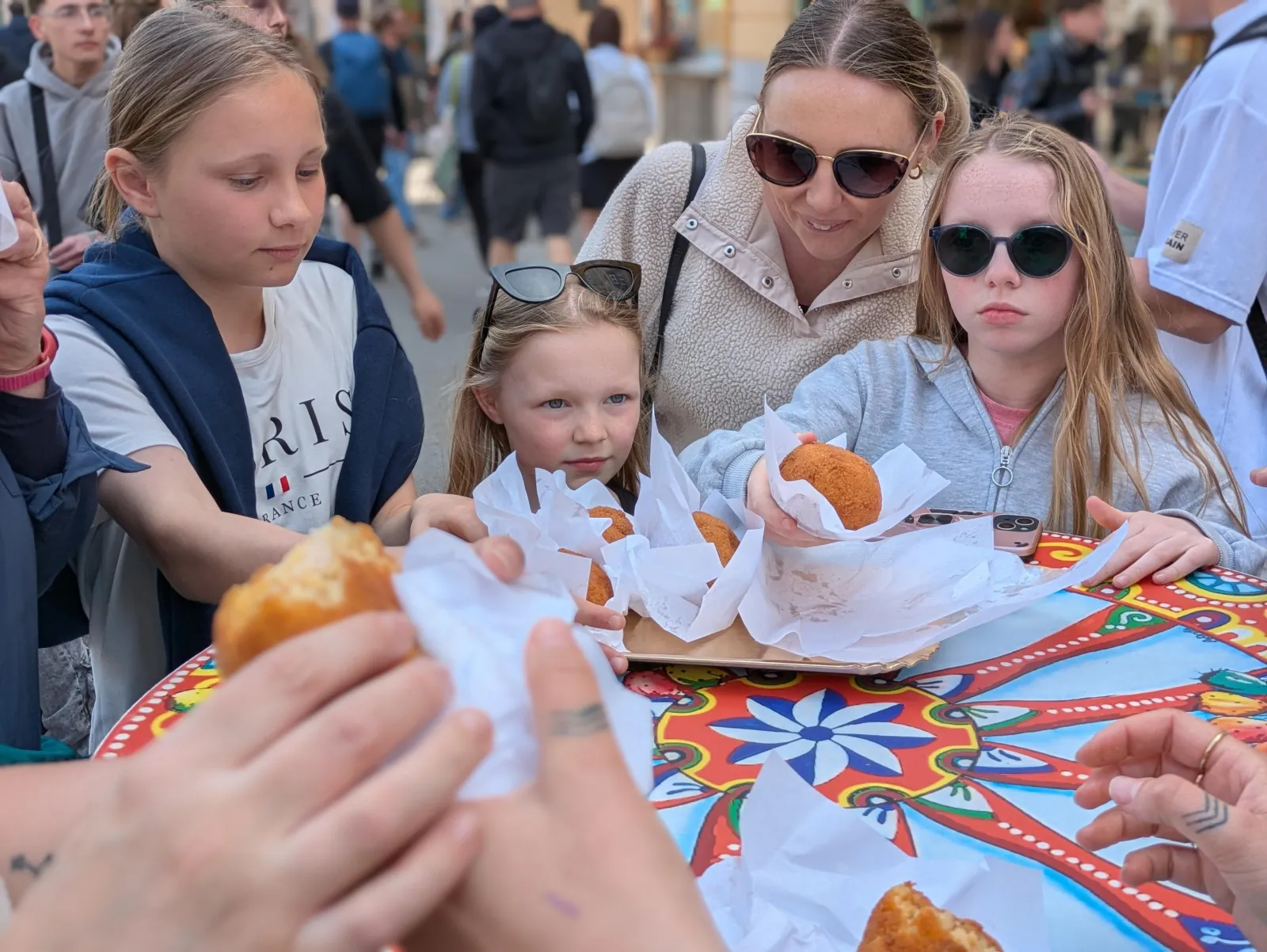 A family shares arancine at a painted cart table