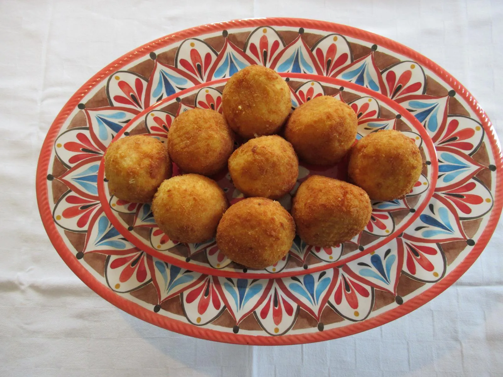 A plate of arancine on a painted ceramic dish