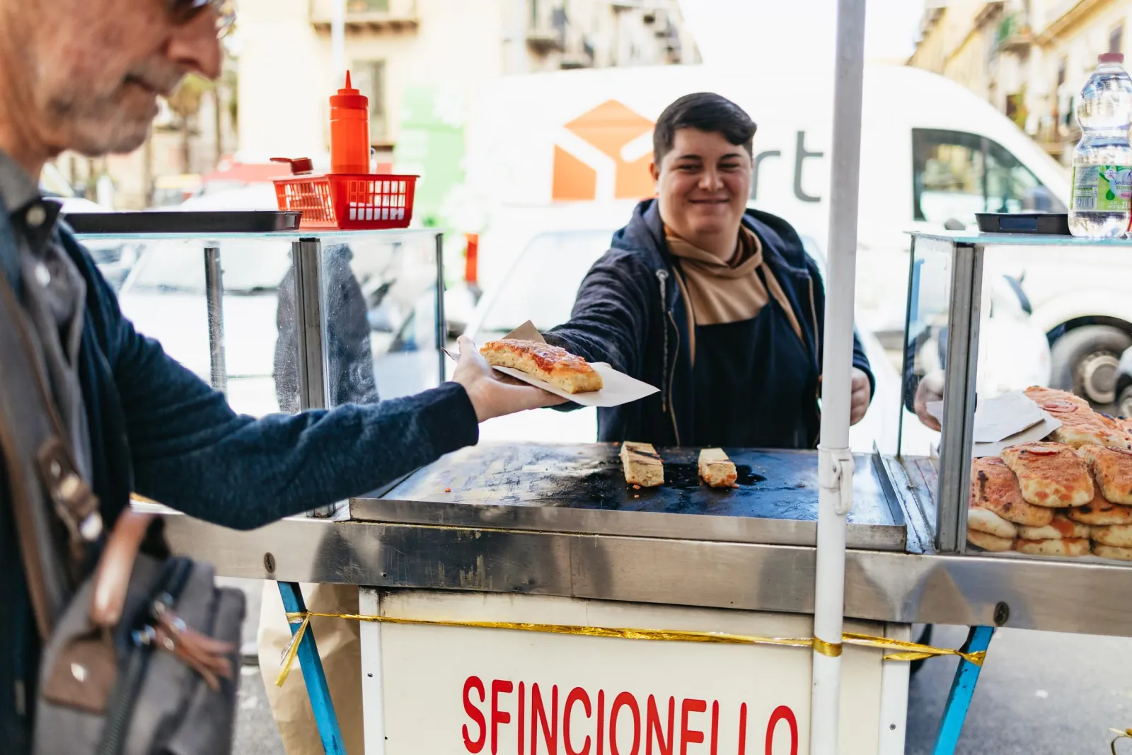 A vendor hands over sfincionello from a street cart