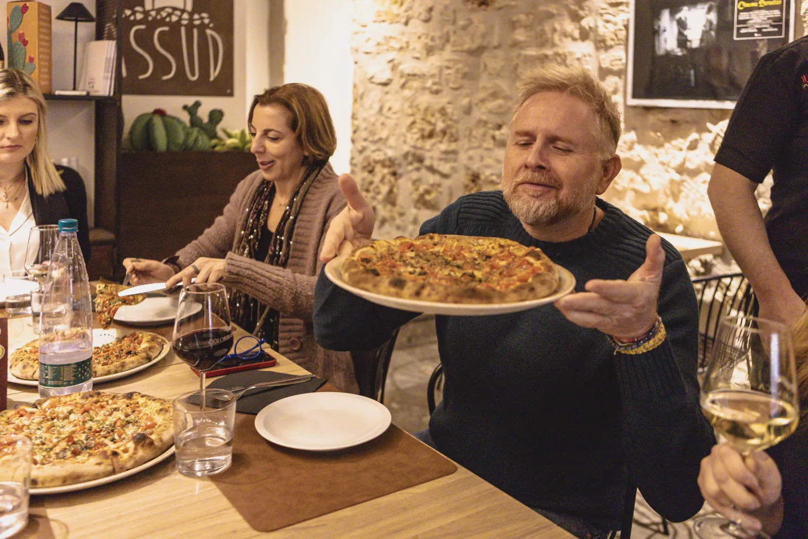 A guest presents a pizza at the evening tour dinner table