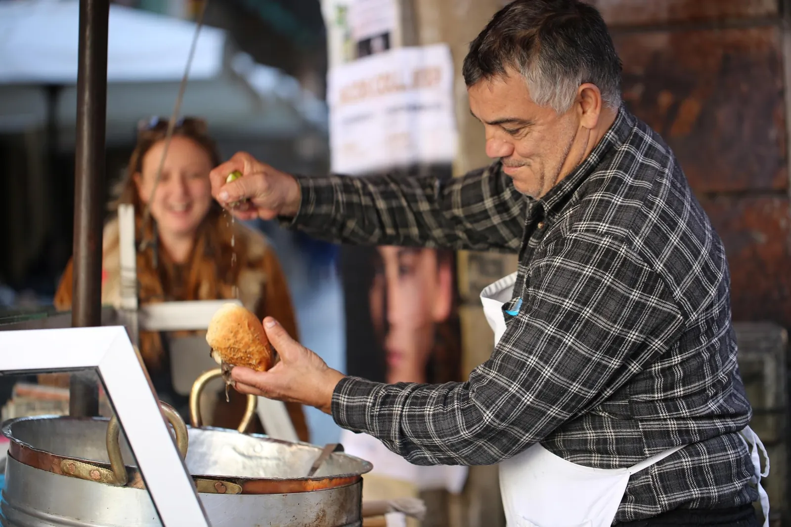 A street food cook lifts a fried arancina from the oil at a Palermo stall