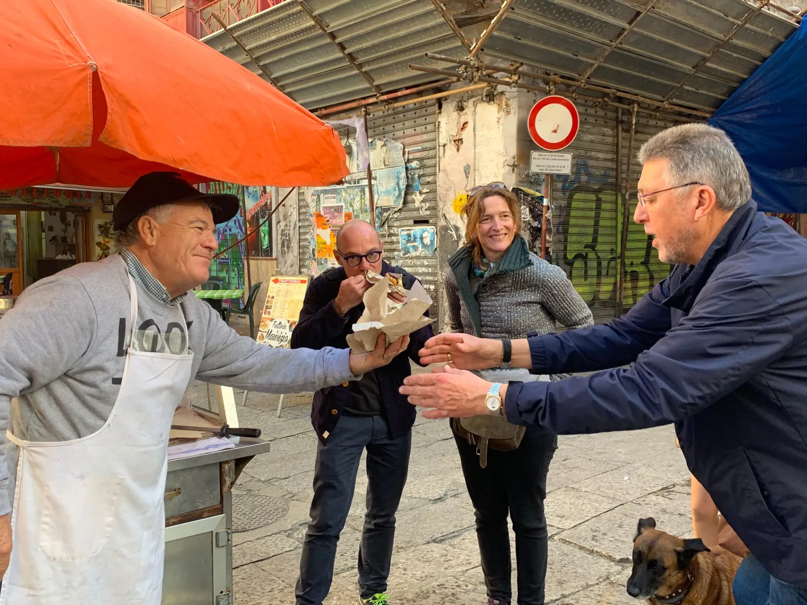 Guests on the tour sharing street food with a vendor in the Vucciria market