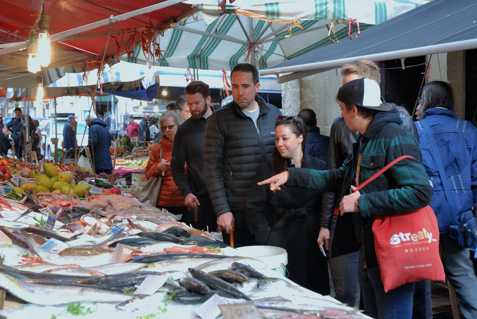 The group stops at a fish stall in a Palermo street market